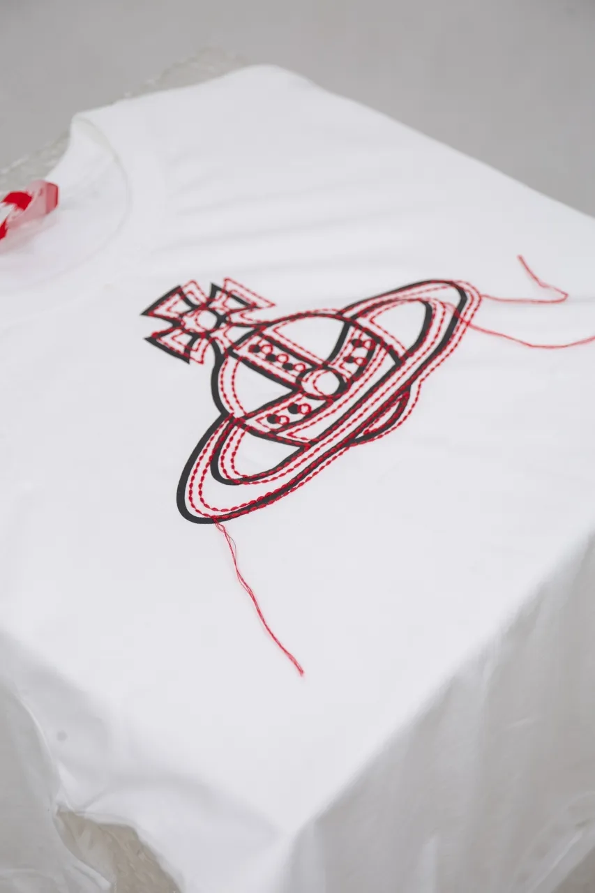 vivienne Westwood Queen Mother's new 2025 spring and summer Japanese limited-edition tassel embroidered short-sleeved T-shirt. The appearance of the appearance reveals the uninhibited image and high street trends. It has a loose and casual style, a short front and long back design, a small slit on the hem on both sides, and the iconic Saturn shape on the chest. The cross crown ball is added with a very futuristic satellite ring, just like Saturn, which collides with the prominent colors of the clothes. The non-overlapping Saturn pattern is outlined with red embroidery, which is visually dazzling. It also has a few tassels to complete the unconventional personality. 240g 32 count high-density double yarn cotton, comfortable and breathable fabric Size: XS-L Color: white, black